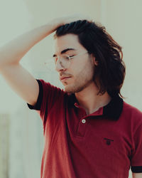 Young man looking away against wall