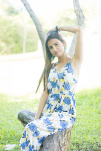 Portrait of young woman standing against tree