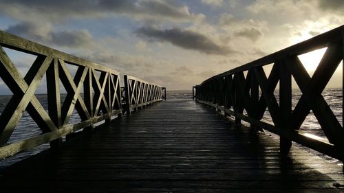 Footbridge over sea against sky