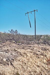 Low angle view of electricity pylon against clear blue sky