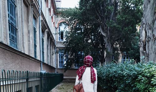 Rear view of woman standing by building