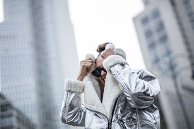 Low angle view of cheerful woman wearing warm clothing in city