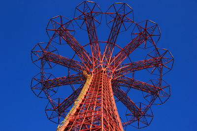 Low angle view of amusement park ride against clear blue sky