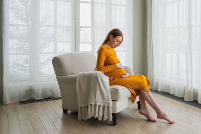 Portrait of young woman sitting on sofa at home