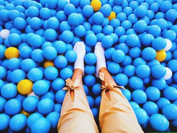 Low section of woman standing amidst balls