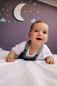 Portrait of cute baby boy lying on bed at home