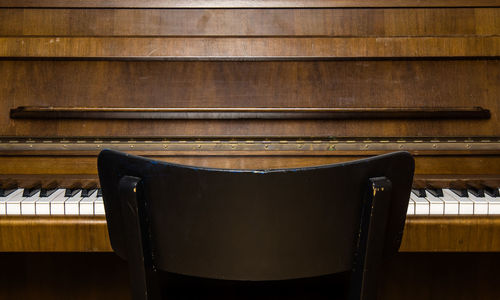 Close-up of chair against piano
