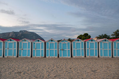 Beach huts by sea against sky. small blue houses in a row. italian vacation