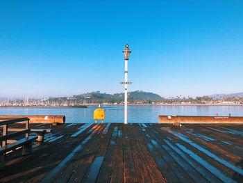 Pier on lake against clear blue sky