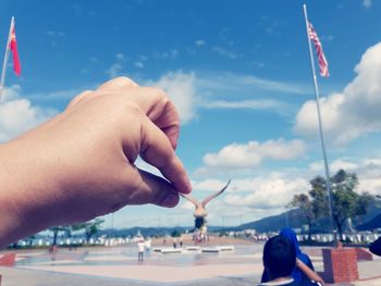 Close-up of hand holding flag against sky