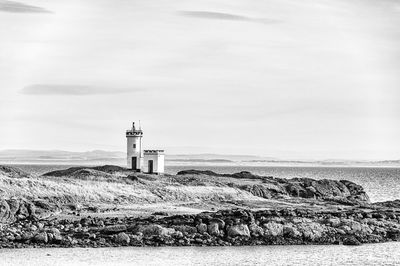 Lighthouse on beach against sky