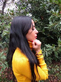 Young woman looking away while standing on tree