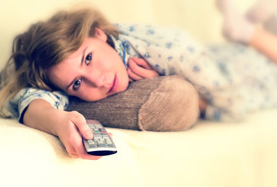 Portrait of young woman lying on bed at home