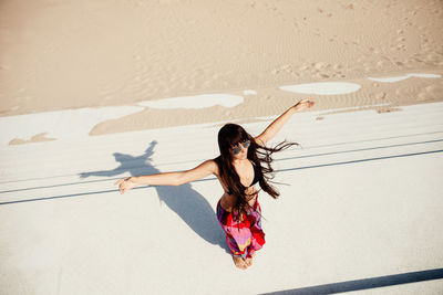 High angle view of woman with arms outstretched standing on steps by beach