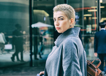 Portrait of young woman looking away in city