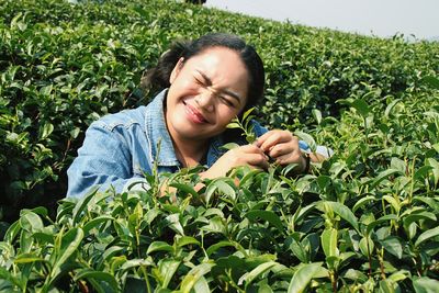 Young woman making face amidst tea crops during sunny day