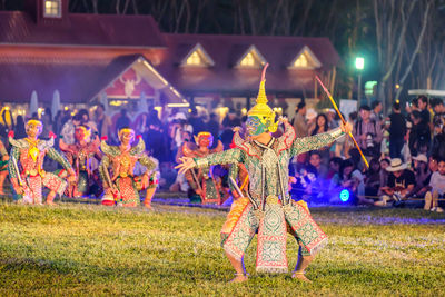 People in illuminated traditional clothing at night