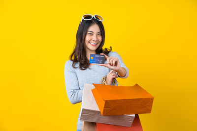 Portrait of a smiling young woman against yellow background