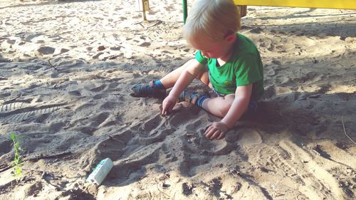 High angle view of boy playing on sand at beach