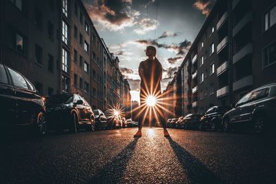 Rear view of woman standing on road in city against sky