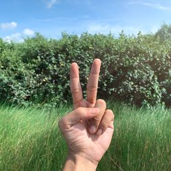Midsection of person hand on grass against field