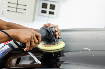 Cropped hand of mechanic polishing car 