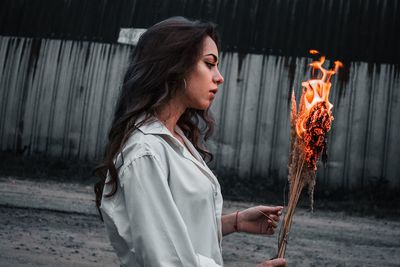 Side view of young woman holding cigarette outdoors