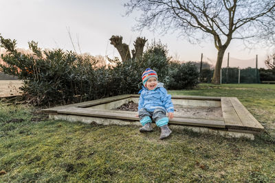 Full length of girl wearing warm clothing sitting outdoors