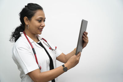 Young woman using mobile phone against white background