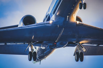 Low angle view of airplane flying against blue sky