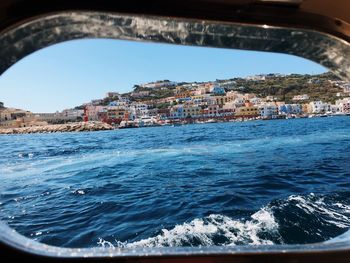 Sea by buildings against clear sky