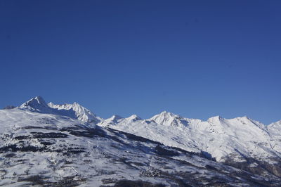 Scenic view of snowcapped mountains against clear blue sky