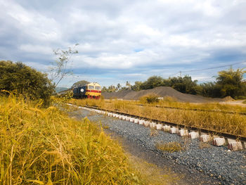 Car on road amidst field against sky