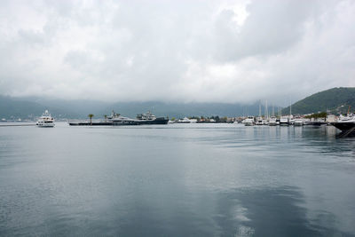 Boats at harbor against cloudy sky