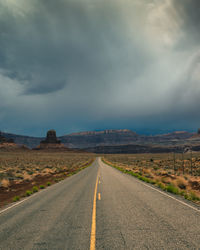 Long straight road in utah with dramatic clouds and rain rolling in, vertical image.