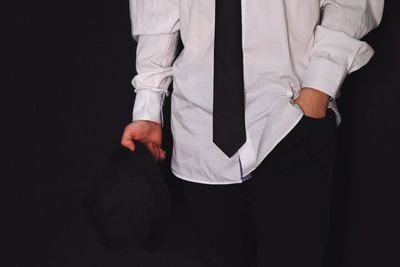 Midsection of man standing against black background