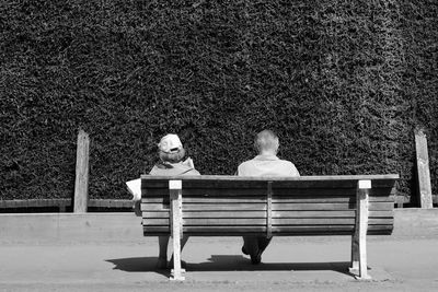Rear view of couple sitting on bench at park