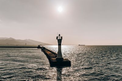 Lighthouse by sea against sky