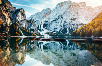 Boats in lake against snowcapped mountains