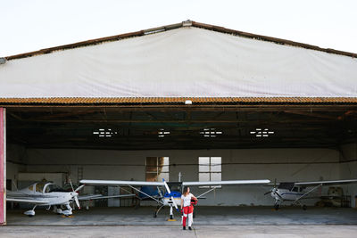 Young female skydiver in a plane hangar surrounded by planes