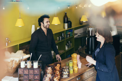 High angle view of happy customer and owner standing in coffee shop