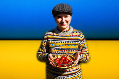 Portrait of young woman standing against yellow background