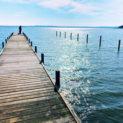 Wooden jetty on pier over sea against sky