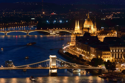 Illuminated bridge over river in city at night