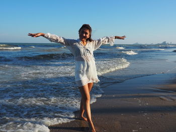 Full length of happy woman standing on beach