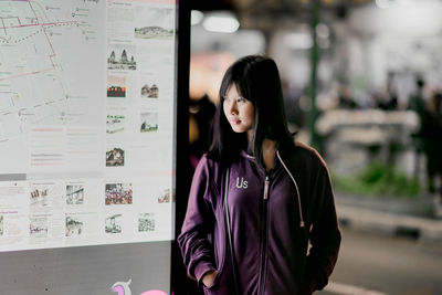 Young woman looking while standing by map