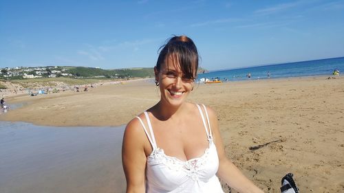 Portrait of smiling young woman on beach against sky