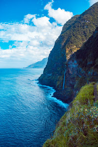 Scenic view of sea and mountains against blue sky