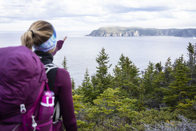 Female backpacker points at cove on east coast trail in newfoundland