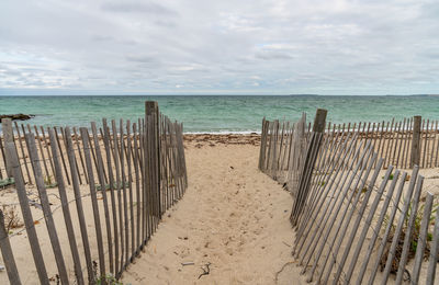 Wooden posts on beach against sky